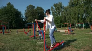 Çocuk parkında beden eğitimi yapan genç ve güzel bir kadın. Güzel Kadın Vücut Çalışması. Sabah Baharı Güneşli Günü. 2x Yavaş çekim 60fps 4K