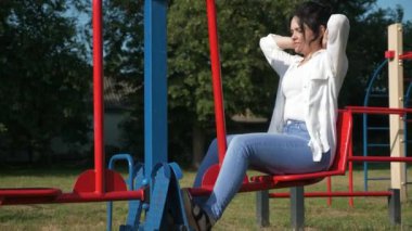 Çocuk parkında beden eğitimi yapan genç ve güzel bir kadın. Güzel Kadın Vücut Çalışması. Sabah Baharı Güneşli Günü. 2x Yavaş çekim 60fps 4K