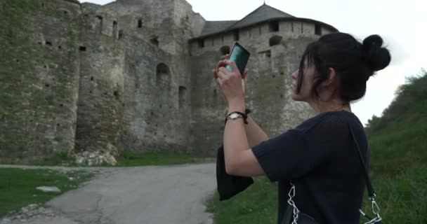 女性観光客は 古い中世の城砦のスマートフォンで写真撮影します 女性旅行観光 カミネツ ポディルスキー ウクライナのヨーロッパ人 夏の夜 — ストック動画