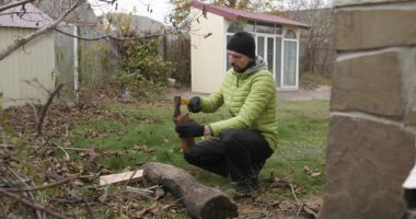 Man, arka bahçede baltayla odun kesiyor. Ağır çekim. 60 fp 10-bit.