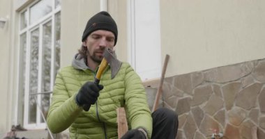 Man, arka bahçede baltayla odun kesiyor. Ağır çekim. 60 fp 10-bit.