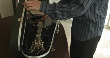 Erkek müzisyen özenle enli bir şekilde enstrümanla ilgileniyor. Mandolin 4K 10-bit 'ten Toz Temizle