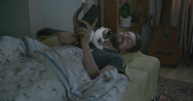 Adam Smartphone ve Kitten ile yatakta uyanıyor. 4K 10-bit