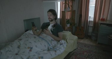 Adam Smartphone ve Kitten ile yatakta uyanıyor. 4K 10-bit