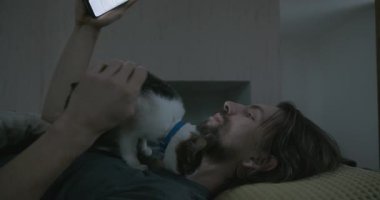 Adam Smartphone ve Kitten ile yatakta uyanıyor. 4K 10-bit