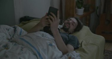 Adam Smartphone ve Kitten ile yatakta uyanıyor. 4K 10-bit