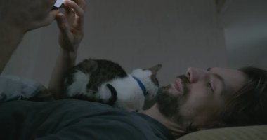 Adam Smartphone ve Kitten ile yatakta uyanıyor. 4K 10-bit