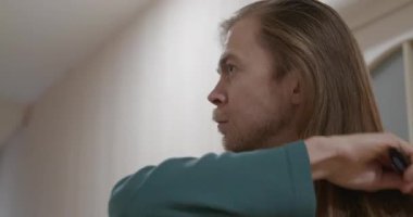 Uzun saçlı adam saçını taradı. Saç stili 4K 10-bit.