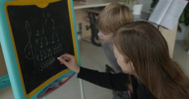 Male Teacher Gives Music Lesson for a Child. Man is Teaching Kid to Play Musical Instrument. 4K 10-bit