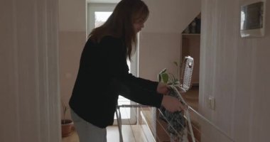 Genç adam kurutucuya çamaşır asıyor. 4K 10-bit