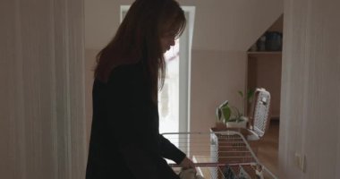 Genç adam kurutucuya çamaşır asıyor. 4K 10-bit