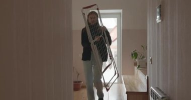 Genç adam kurutucuya çamaşır asıyor. 4K 10-bit