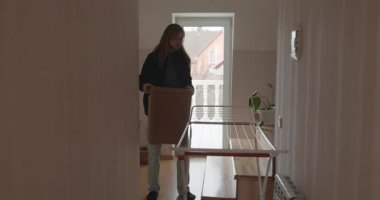 Genç adam kurutucuya çamaşır asıyor. 4K 10-bit