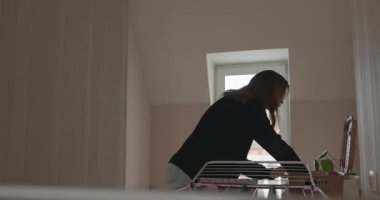 Genç adam kurutucuya çamaşır asıyor. 4K 10-bit