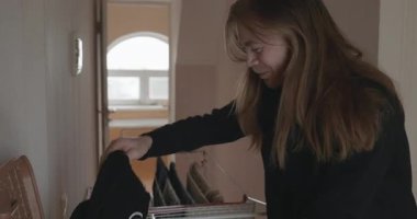 Genç adam kurutucuya çamaşır asıyor. 4K 10-bit