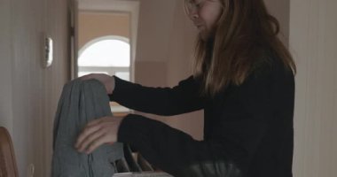 Genç adam kurutucuya çamaşır asıyor. 4K 10-bit