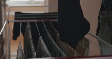 Genç adam kurutucuya çamaşır asıyor. 4K 10-bit