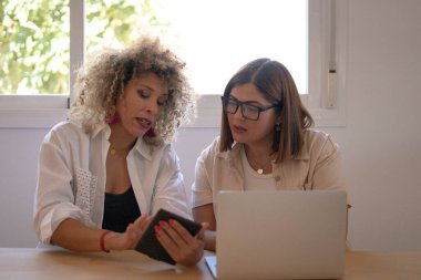 Bir projede işbirliği yapan iş kadınları, dijital tablet ve dizüstü bilgisayarda bilgi görenler