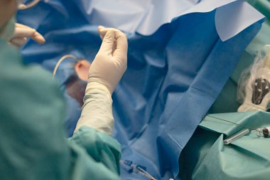 Cerrahın eldivenli elleri steril bir ortamda tıbbi müdahaleye hazırlanıyor.