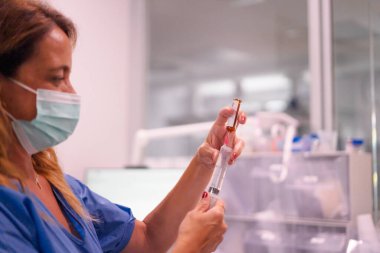 Hemşire tıbbi bir ortamda küçük bir şişeden ilaç alıyor.