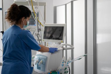 Hemşire yoğun bakım ünitesindeki solunum cihazının ayarlarını ayarlıyor.