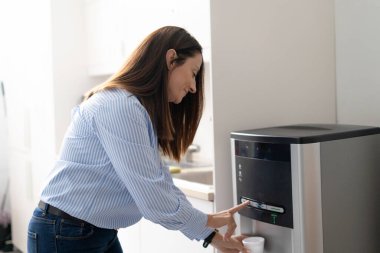 Ofis mutfağında su içen bir kadın.