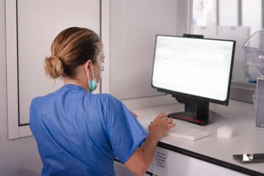 Klavyede tıbbi uzman daktilo kullanıyor, hastane ortamında hasta verilerini işliyor