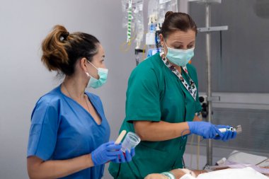 Hemşireler yoğun bakımda olan bir hastaya tıbbi bir işlem uyguluyorlar.