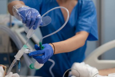 Tıbbi profesyonel eldivenli eller hasta bakımı için solunum ekipmanlarını bağlıyor