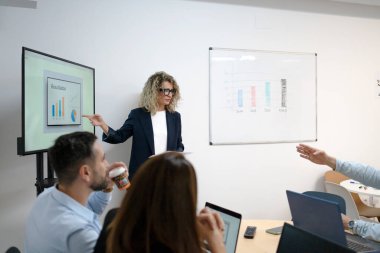 Meslektaşlarıyla istatistiksel çizelgeleri ofis yönetim kurulunda tartışan bir iş adamı.