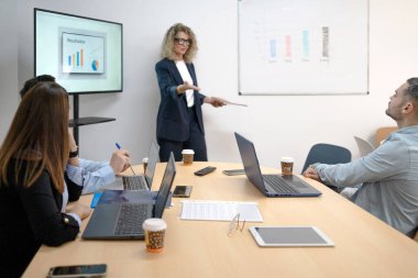 Şirket toplantısında çeşitli takımlara veri analizi sunan iş kadını