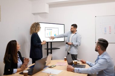 Bir sunum sırasında iş birliği yapan ve mali sonuçları tartışan iş adamları