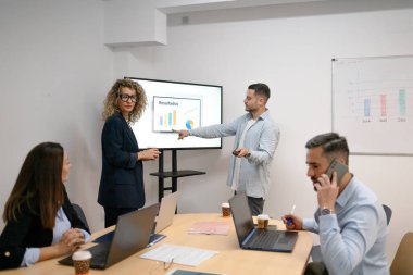 İş arkadaşları modern bir ofiste finansal verileri tartışıyor ve işbirliği yapıyorlar.