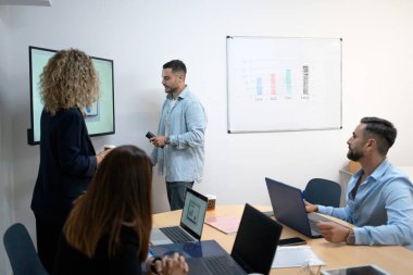 Çeşitli iş adamları gündelik ofis ortamında çizelge ve verileri tartışır