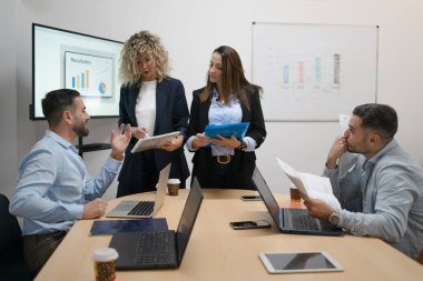 Ofis toplantısı sırasında veri analizi ve işbirliği yapan iş adamları