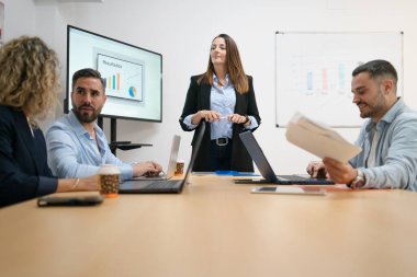 Bir ofis toplantısında pazarlama stratejisi ve iş sonuçlarını tartışan bir grup meslektaş