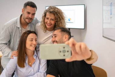 Çeşitli iş arkadaşları modern bir ofiste gülümsüyor ve özçekim için poz veriyorlar.