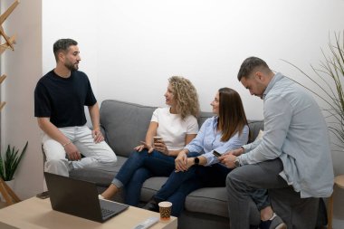 Modern, rahat bir ofis alanında tartışan ve birlikte çalışan dört profesyonel.