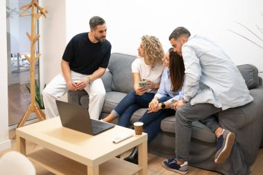 Bir grup iş arkadaşı modern bir ofis salonunda fikirlerini tartışıyor ve işbirliği yapıyorlar.