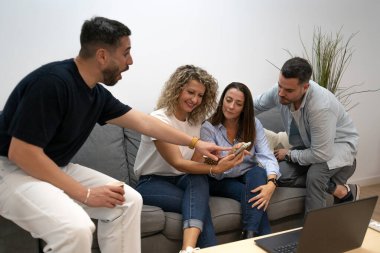 Arkadaşların kapalı alandaki akıllı telefonların içeriğine şaşırarak ve sosyalleşerek tepki göstermeleri