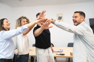 Mutlu iş adamları bir ofis toplantısında birlik ve başarı içinde el ele tutuşuyor.