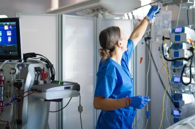 Hemşire, yoğun bakımdaki tıbbi ekipmanlara bağlı damar içi torba ayarlıyor.