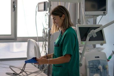 Hemşire yoğun bakım odasında hasta bakımı için tıbbi ekipman ayarlıyor.