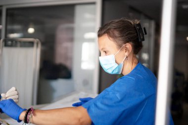 Tıp üniformalı hemşire maske ve eldiven takıyor.