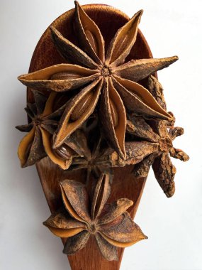 Tahta kaşıkta yıldız anason kapsüllerinin yüksek çözünürlüklü makro görüntüsü, doğal yıldız şekillerini ve detaylı dokusunu gösteriyor..