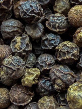Kırışıklık dokusunu ve sıcak kahverengi tonlarını gösteren, baharat, yemek pişirme ve yemek arkaplanı kavramları için mükemmel siyah karabiberlerden oluşan uç makro..