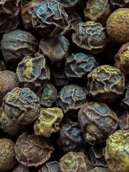 Kırışıklık dokusunu ve sıcak kahverengi tonlarını gösteren, baharat, yemek pişirme ve yemek arkaplanı kavramları için mükemmel siyah karabiberlerden oluşan uç makro..