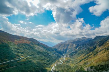 İsviçre Alpleri 'nde önünde yol olan bir dağ sırası. Yol boş ve ortada beyaz bir çizgi var.