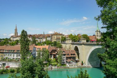 İsviçre 'deki Bern şehrinin manzarası. Aare Nehri ve köprünün bir kısmı görülebilir durumda. Hava güneşli ve açık, gökyüzü biraz bulutla mavi..