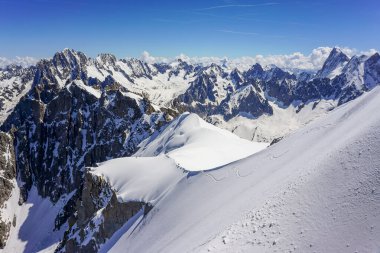Fransız Alpleri 'ndeki tırtıklı, yüksek, karla kaplı dağların manzarası. Fotoğraf Aiguille du Midi dağından çekildi. Chamonix. Ayak izleriyle kaplı büyük kar görülebilir.